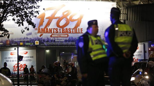 Polizisten stehen vor einem Veranstaltungsort mit Plakaten für das Musical „1789, les amants de la Bastille“.