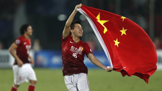 Ein Fußballspieler hält eine chinesische Flagge hoch.