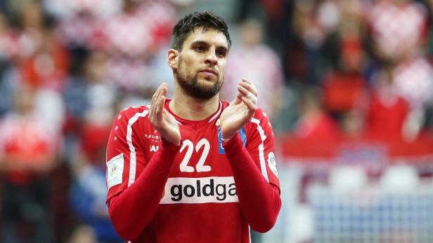 Ein Handballspieler in rotem Trikot klatscht Beifall.