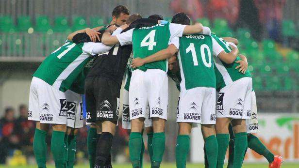 Eine Fußballmannschaft steht im Kreis und umarmt sich.