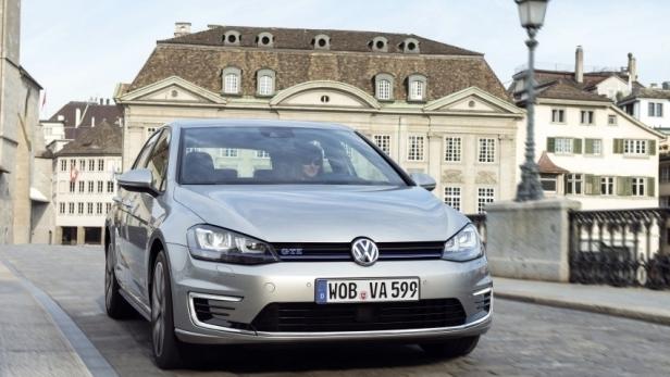 Ein silberner VW Golf GTE fährt durch eine Stadt.
