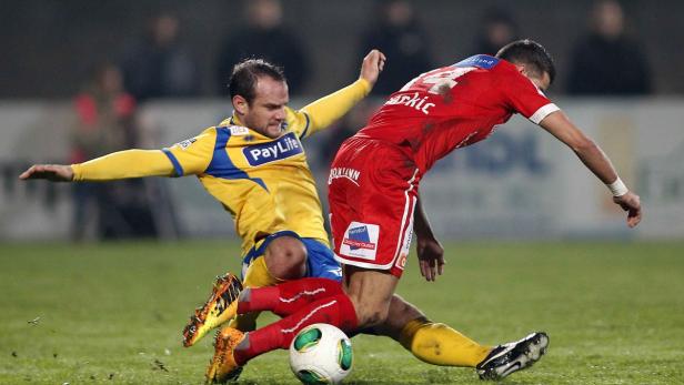 Zwei Fußballspieler kämpfen um den Ball auf dem Spielfeld.