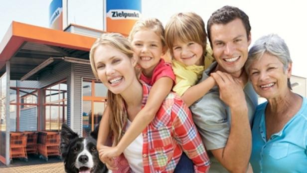 Eine lächelnde Familie mit Hund steht vor einem Zielpunkt-Markt.