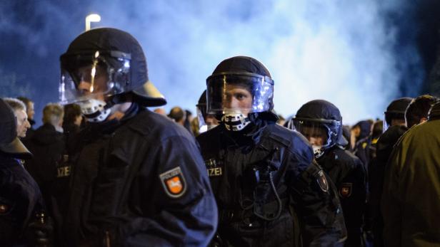 Mehrere Polizisten mit Helmen stehen in einer Menschenmenge.