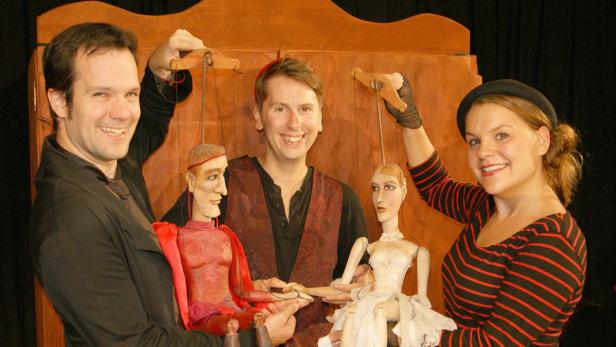 Drei Puppenspieler präsentieren ihre Marionetten auf der Bühne.