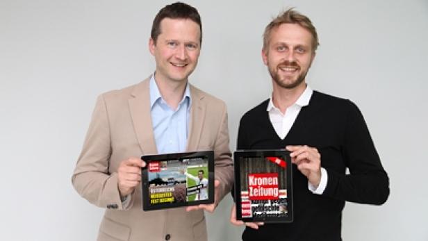 Zwei Männer präsentieren Tablets mit der „Kronen Zeitung“.