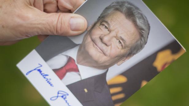 Eine Hand hält ein signiertes Porträt von Joachim Gauck.