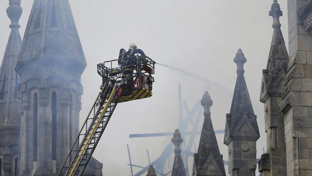 Ein Feuerwehrmann löscht ein Feuer in einem hohen Gebäude mit vielen Türmchen.