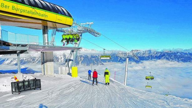 Die 8er Burgstallalm-Seilbahn bringt Skifahrer auf den Berg, über einer Wolkendecke.