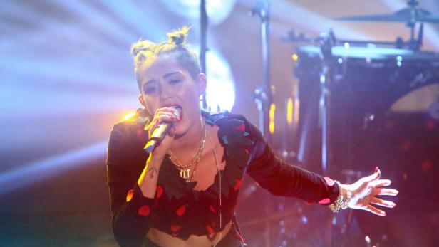 Miley Cyrus singt während eines Konzerts in ein Mikrofon.
