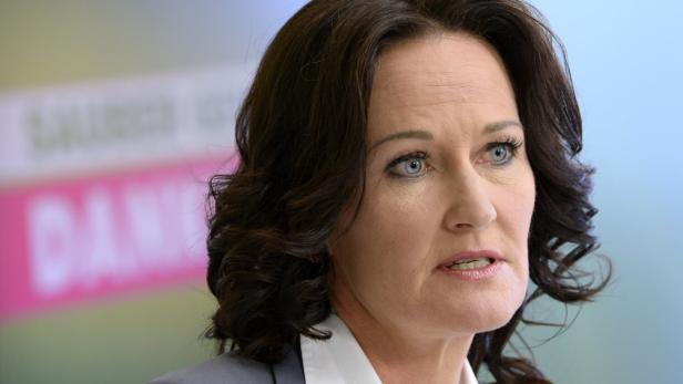 Nahaufnahme einer Frau mit dunklen, gewellten Haaren und hellblauen Augen.