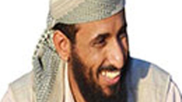 Ein lächelnder Mann mit Bart und traditioneller Kopfbedeckung.