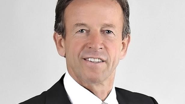 Ein Mann in Anzug und Krawatte lächelt in die Kamera.