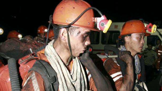 Erschöpfte Bergleute nach einem Minenunglück mit schmutzigen Gesichtern und Helmlampen.