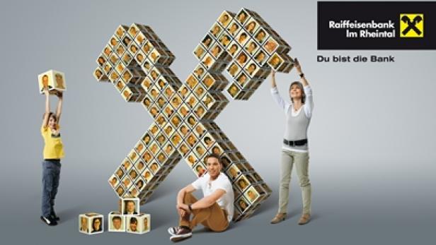 Personen bauen ein großes Symbol aus Würfeln mit Gesichtern für die Raiffeisenbank im Rheintal.