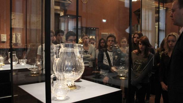 Eine Gruppe von Menschen betrachtet Glaswaren in einem Museum.