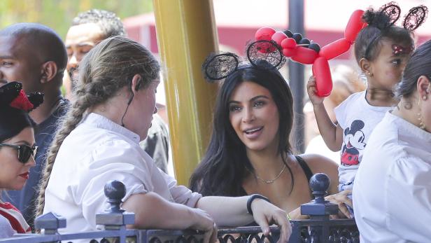 Kim Kardashian mit Familie im Disneyland, alle tragen Mickey-Mouse-Ohren.
