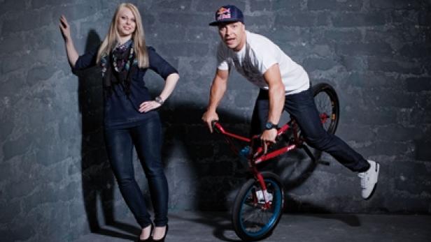 Eine Frau posiert neben einem Mann, der auf einem BMX-Rad steht.