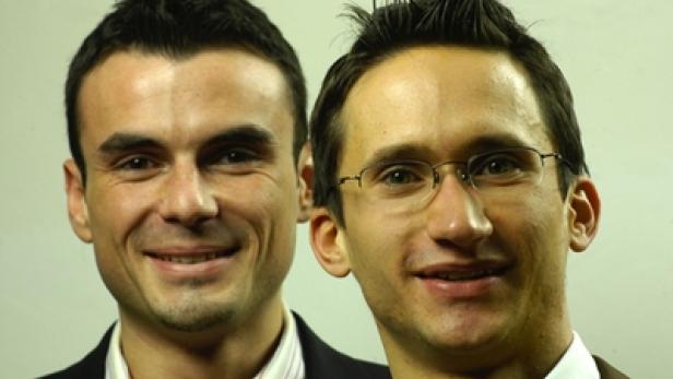 Zwei Männer lächeln in die Kamera, einer trägt eine Brille.