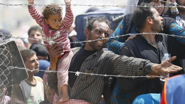 Syrische Flüchtlinge am Stachelbandzaun an der türkischen Grenze.