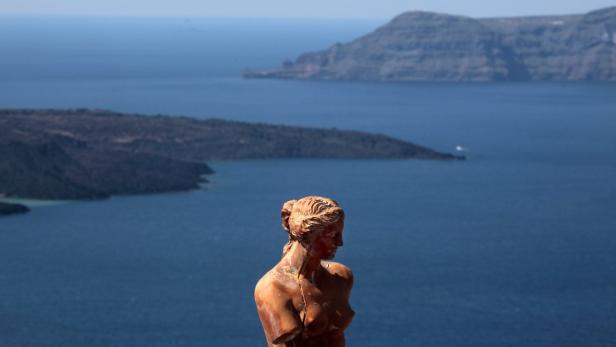 Eine beschädigte Frauenstatue mit Meer und Inseln im Hintergrund.