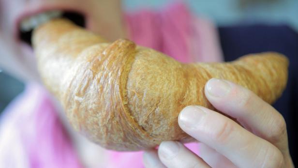 Eine Person isst ein Croissant.