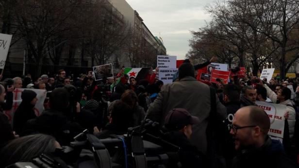 Eine Demonstration mit syrischen Flaggen und Schildern gegen den Krieg in Syrien.