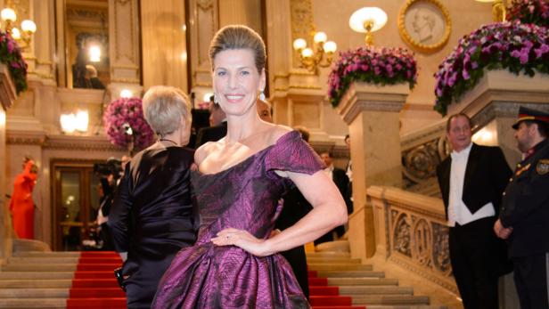 Eine Frau in einem violetten Ballkleid posiert auf einer Treppe bei einer Veranstaltung.