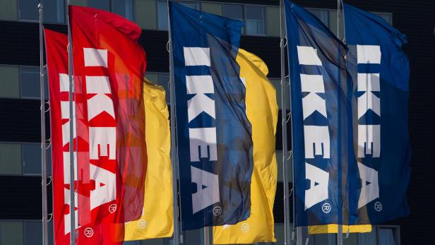 Mehrere IKEA-Flaggen in den Farben Blau, Gelb und Rot wehen vor einem Gebäude.