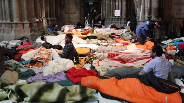 Refugees sit in a mattress camp in Votivkirche church in Vienna January 23, 2013. Some 40 refugees - mostly from Pakistan and Afghanistan - who had been on hunger strike, some since before Christmas, broke their fast on Tuesday night but said they were merely pausing for about a week to regain strength for negotiations. The refugees, who are beeing supported by agencies including Catholic social charity Caritas, want the right to work while they are waiting - sometimes for years - to find out whether they can stay in Austria. REUTERS/Heinz-Peter Bader (AUSTRIA - Tags: SOCIETY IMMIGRATION RELIGION CIVIL UNREST)