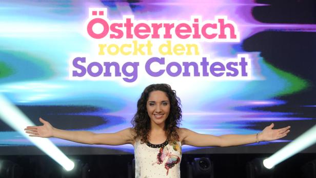 Eine Frau steht vor dem Schriftzug „Österreich rockt den Song Contest“.