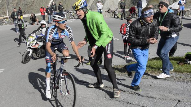 Ein Radfahrer wird während eines Rennens von einem Betreuer angefeuert.