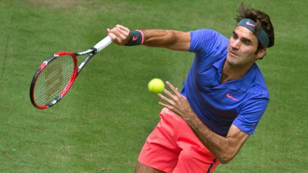 Roger Federer schlägt einen Tennisball auf einem Rasenplatz.