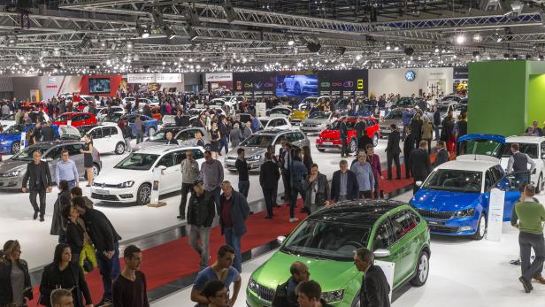 Viele Menschen besuchen einen belebten Automobilsalon mit verschiedenen Automarken wie VW, Skoda und Seat.