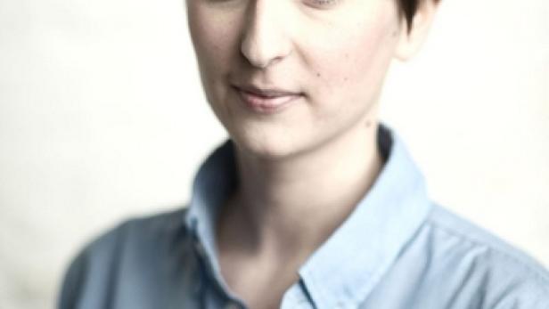 Porträt einer Frau mit kurzem, dunklem Haar und hellblauem Hemd.