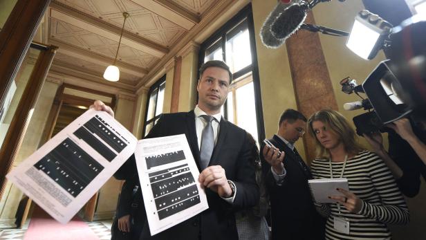 Ein Mann im Anzug präsentiert Dokumente vor einer Gruppe von Journalisten.