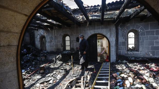 Ein Mann steht in den Überresten eines durch ein Feuer beschädigten Gebäudes.