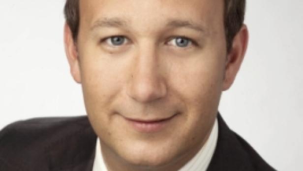 Ein Mann mit Anzug und Krawatte lächelt in die Kamera.