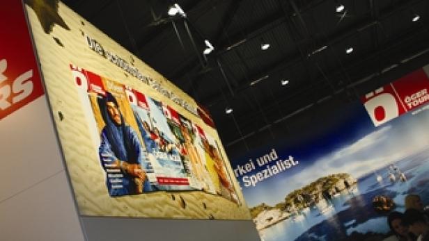 Ein Stand von Öger Tours mit Werbeplakaten und einem Landschaftsbild.