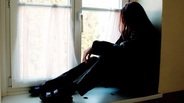 Eine Person sitzt am Fenster und schaut nach draußen.