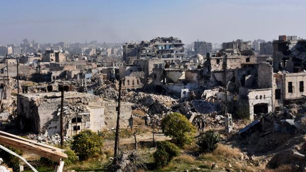 Eine zerstörte Stadtlandschaft mit Trümmern und wenigen Bäumen im Vordergrund.