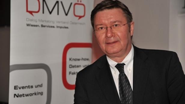 Ein Mann im Anzug steht vor einem Banner des DMVÖ (Dialog Marketing Verband Österreich).