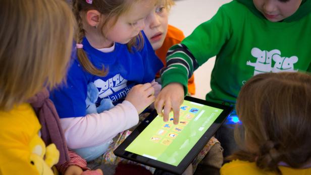 Eine Gruppe Kinder spielt gemeinsam auf einem Tablet.