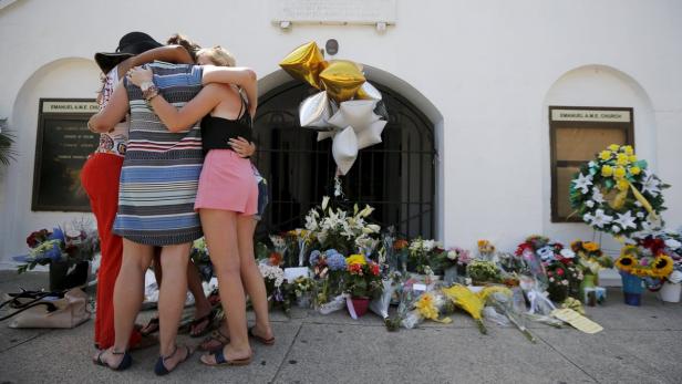 Vor der Emanuel A.M.E. Kirche umarmen sich mehrere Frauen vor Blumen und Ballons.
