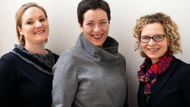 Drei Frauen lächeln in die Kamera.