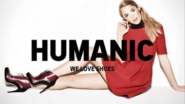 Eine Frau in einem roten Kleid posiert mit Schuhen der Marke Humanic.