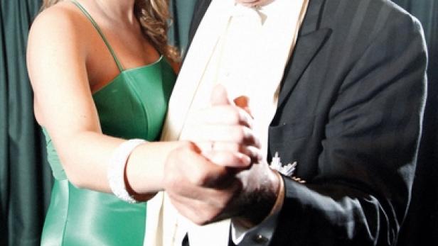 Eine junge Frau im grünen Kleid tanzt mit einem älteren Mann im Anzug.