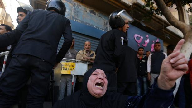 A Muslim woman cries while sitting in front of police officers in front of St. Mark&#039;s Coptic Orthodox Cathedral after an explosion inside the cathedral in Cairo, Egypt December 11, 2016. REUTERS/Mohamed Abd El Ghany