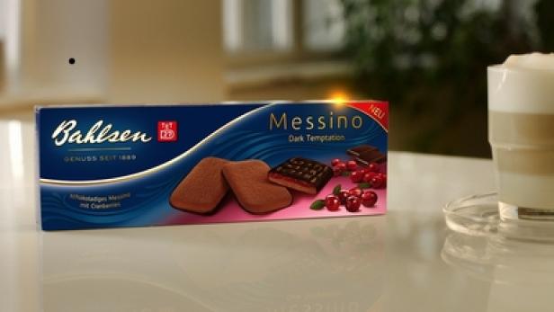 Eine Packung Bahlsen Messino Kekse mit Cranberries steht neben einem Glas Latte Macchiato.