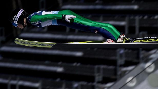 Ein Skispringer in der Luft mit Fischer-Skiern.